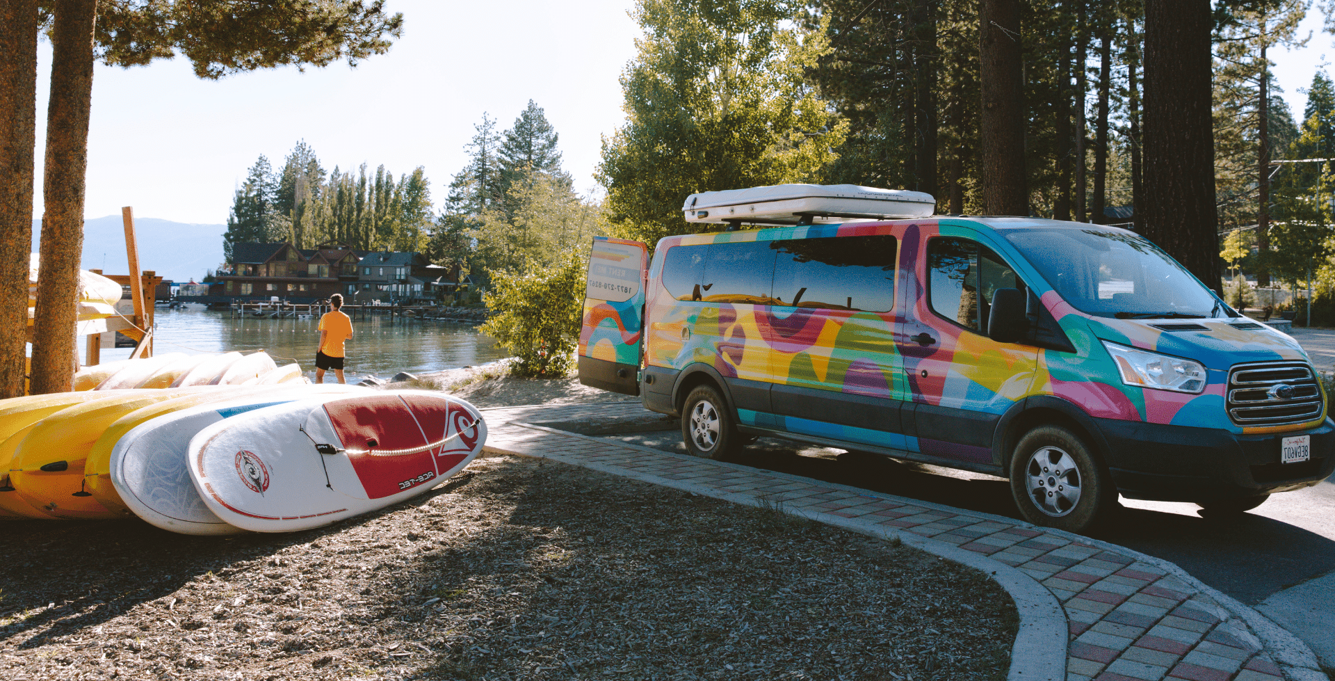 Escape Camper Vans Mesa van parked beside a lake on the Pacific Coast Highway beside paddle boards and kayaks.