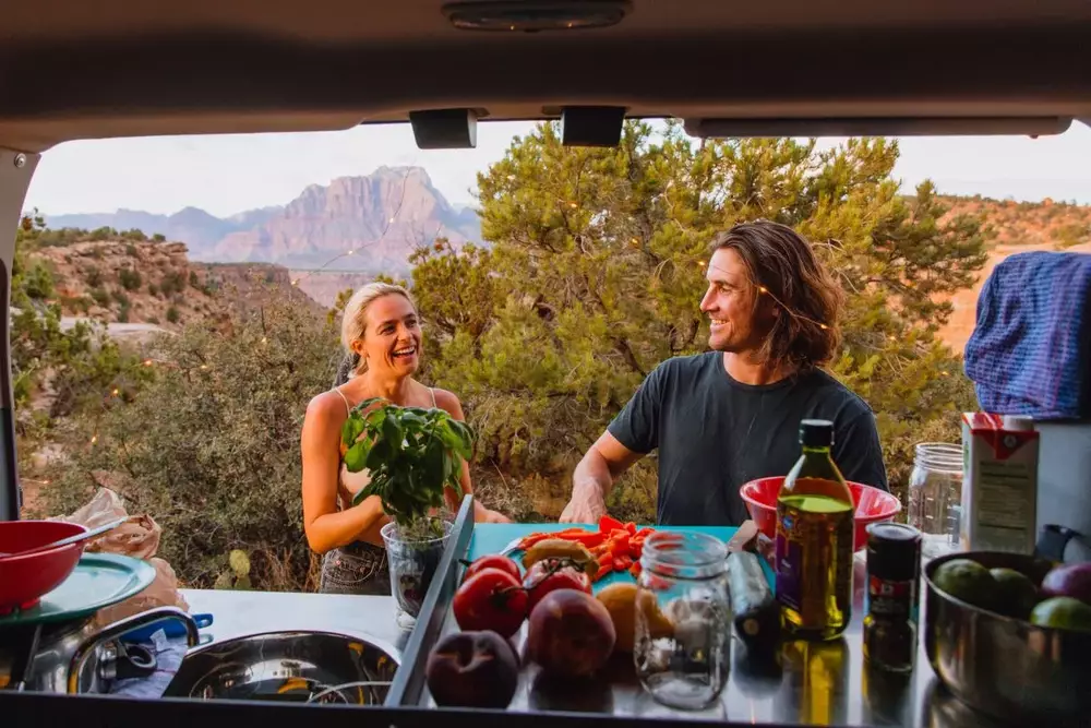 Two people cooking in the desert in an Escape Camper Van.