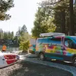 An escape camper van by a lake with paddle boards.