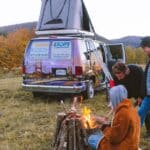 People sitting around a campfire with an Escape Camper Van on a Vermont road trip.