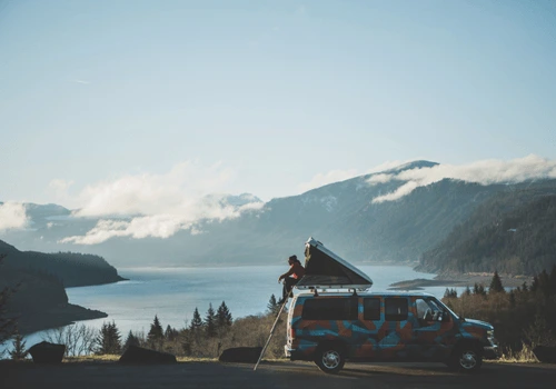 Escape Camper Van parked with roof top sleeper popped up in front of a lake