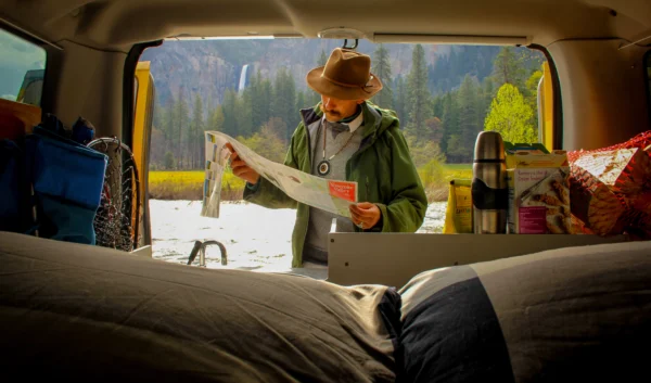 Man reading a map in the back of a camper van. Yosemite National Park.