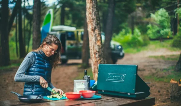 A woman sitting at a table at a campground preparing easy camping meals