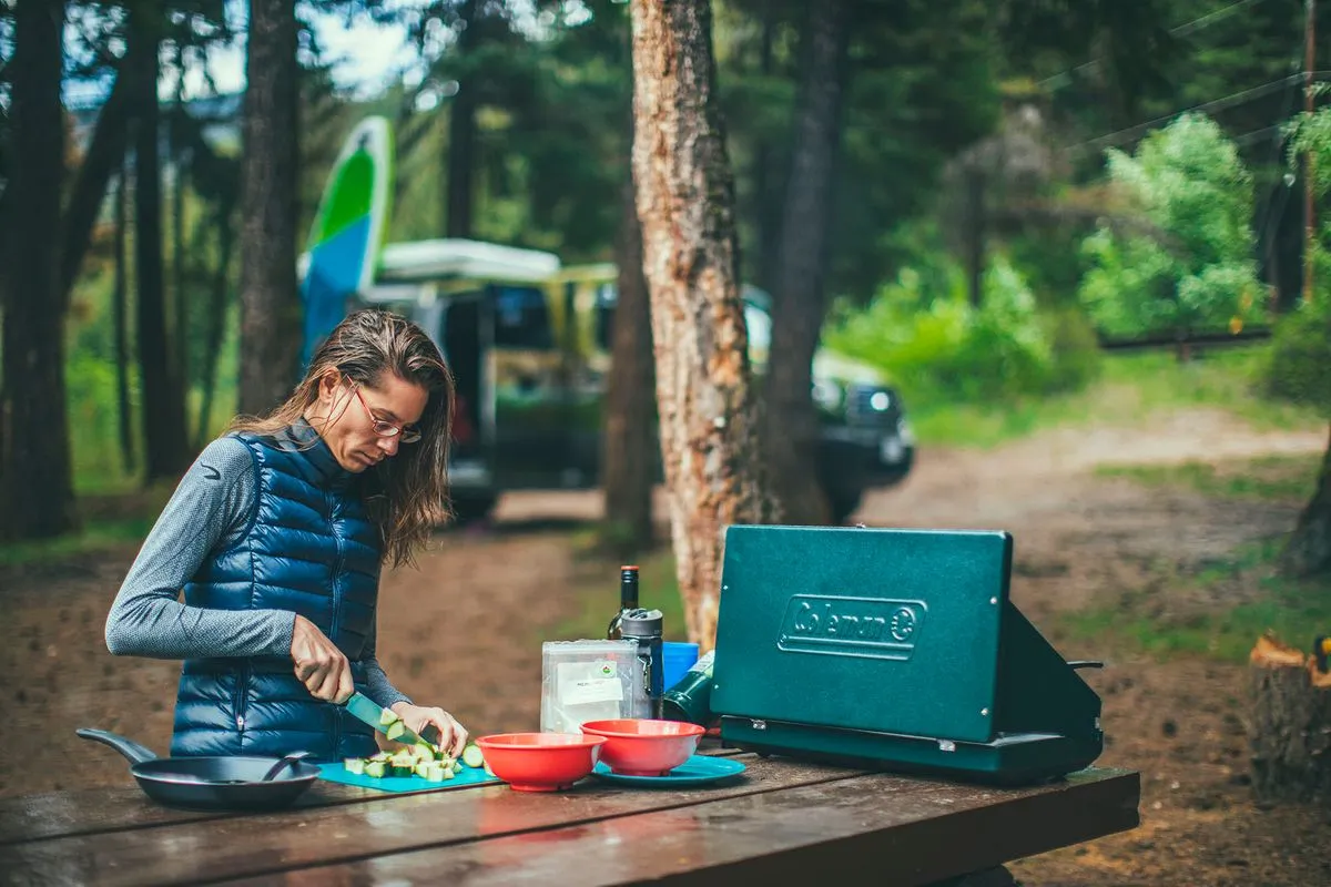 A woman sitting at a table at a campground preparing easy camping meals