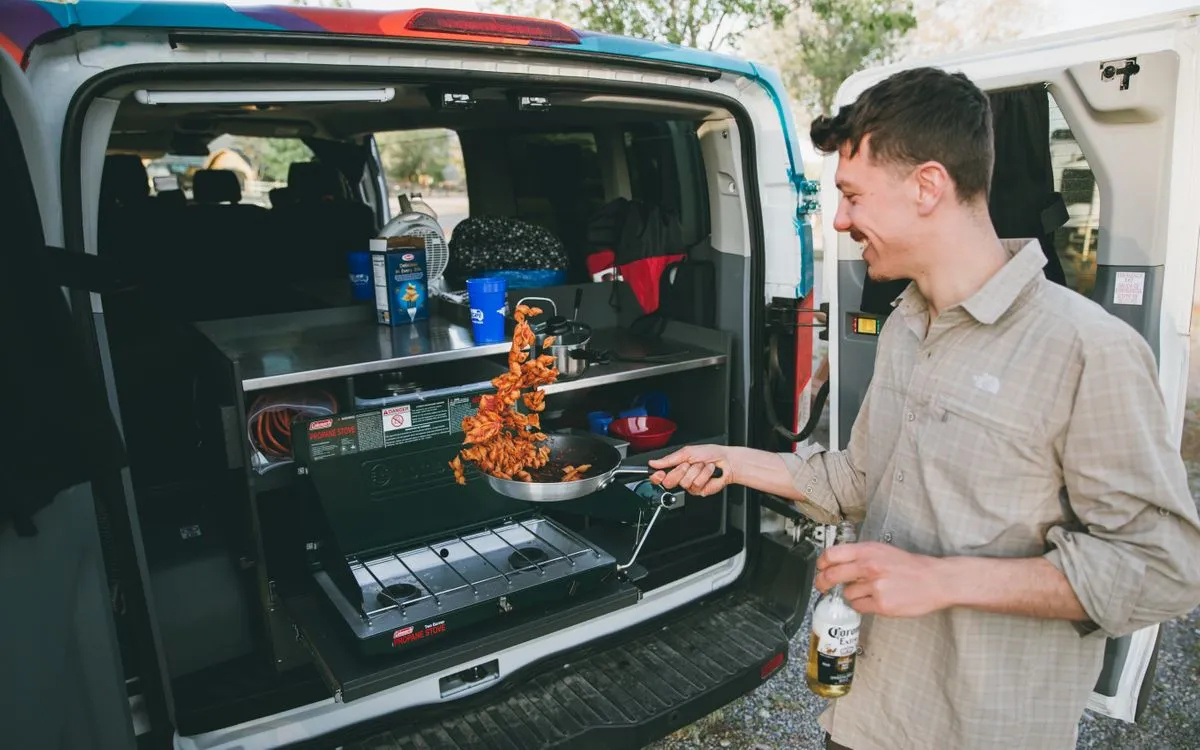 A man making pasta in the back kitchen of an Escape Campervan